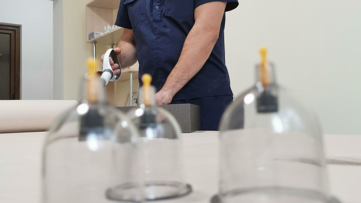 Cupping therapy glasses laid out beside a practitioner in a treatment room